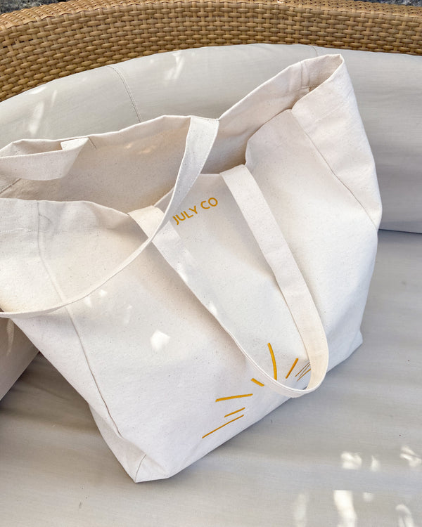The July Tote Bag by The July Co made from 100% heavy weight Fairtrade organic cotton, with side panels for extra space and wide straps for durability. Golden yellow sun embroidery design on front. Perfect beach bag or for travel and weekend breaks.