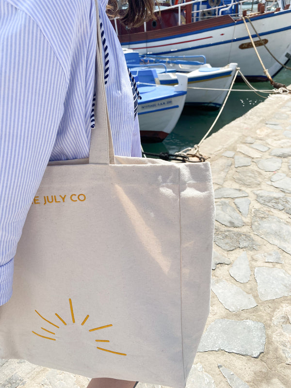 The July Tote Bag by The July Co made from 100% heavy weight Fairtrade organic cotton, with side panels for extra space and wide straps for durability. Golden yellow sun embroidery design on front. Perfect beach bag or for travel and weekend breaks